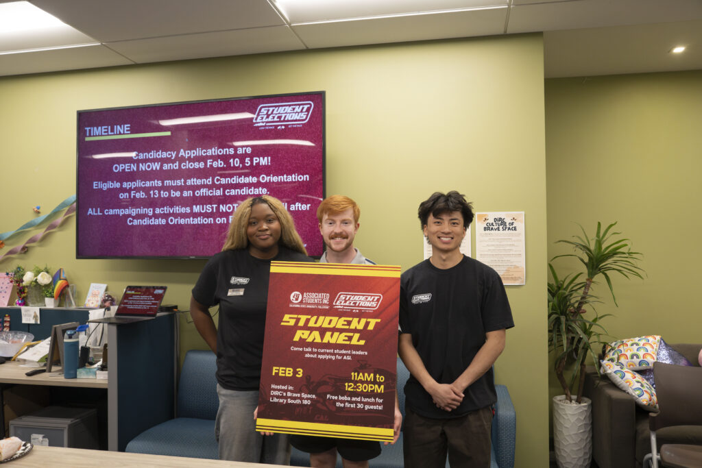 a trio of college students posing with a sign