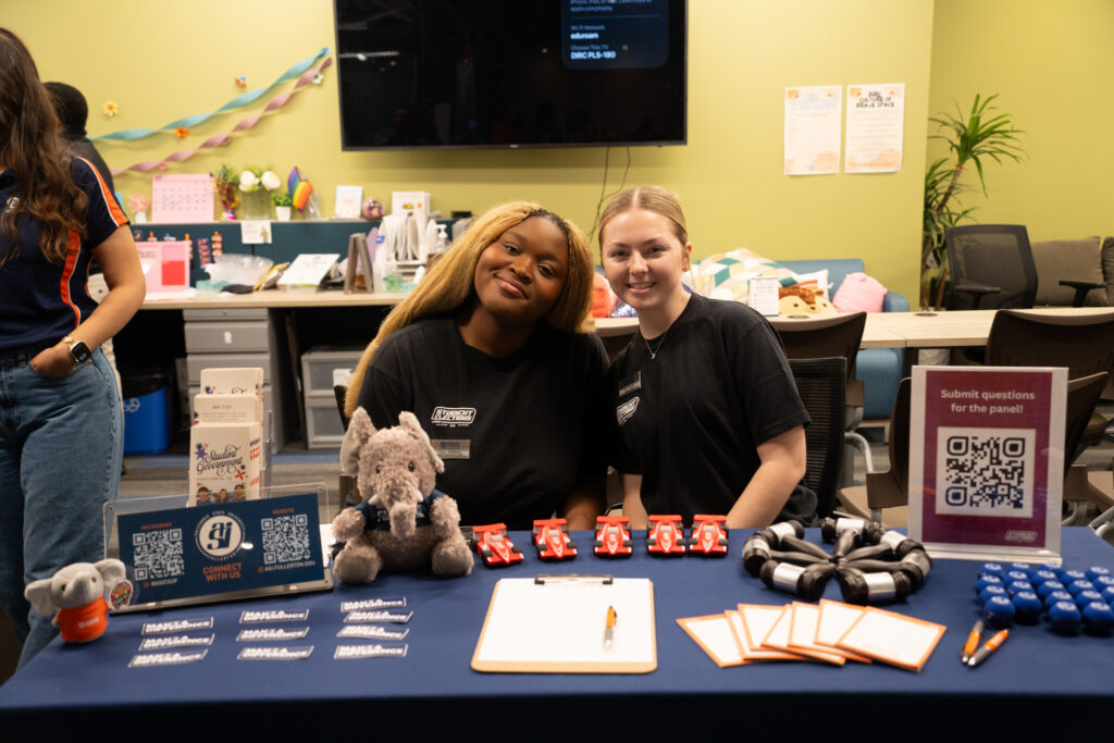 two college students sit at a table and smile