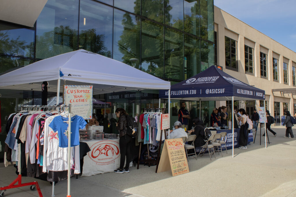 Two tents and a rack of clothes sits in front of glass windows.