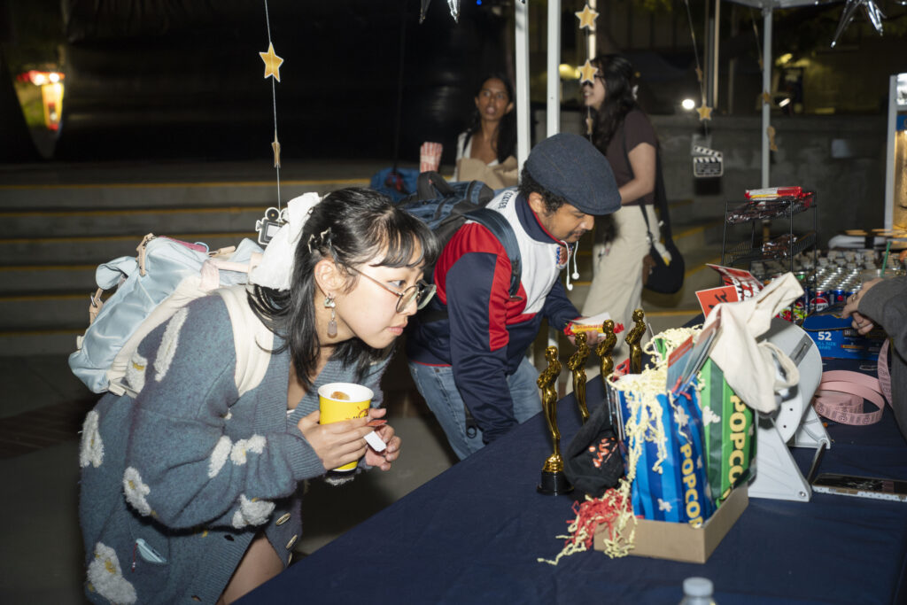 a group of students look at table displays at night 
