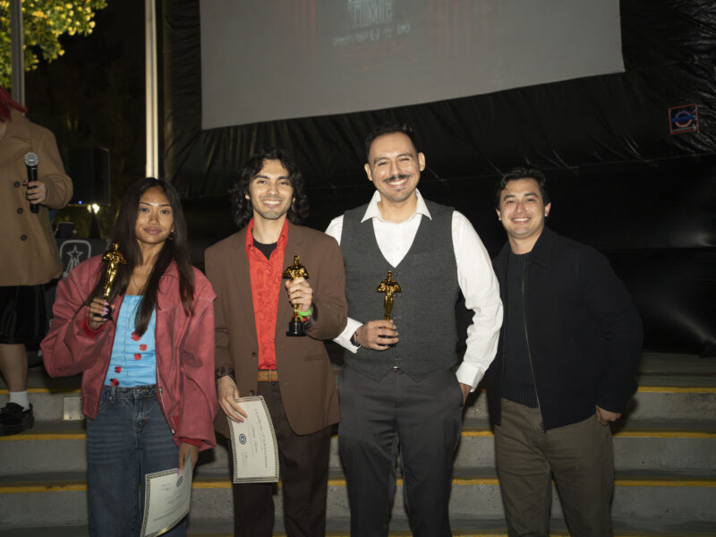 a group of students pose together holding trophies