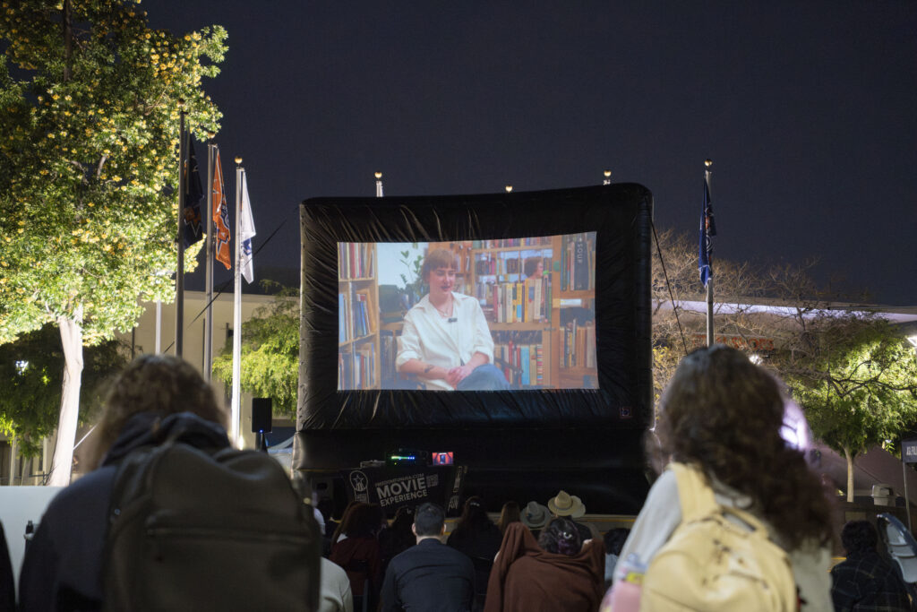 a giant projector outside displaying a movie 