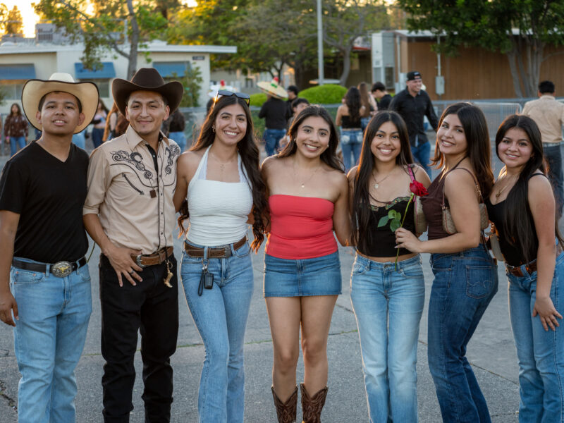 a group of students in cowboy hats and boots pose for a picture holding a rose