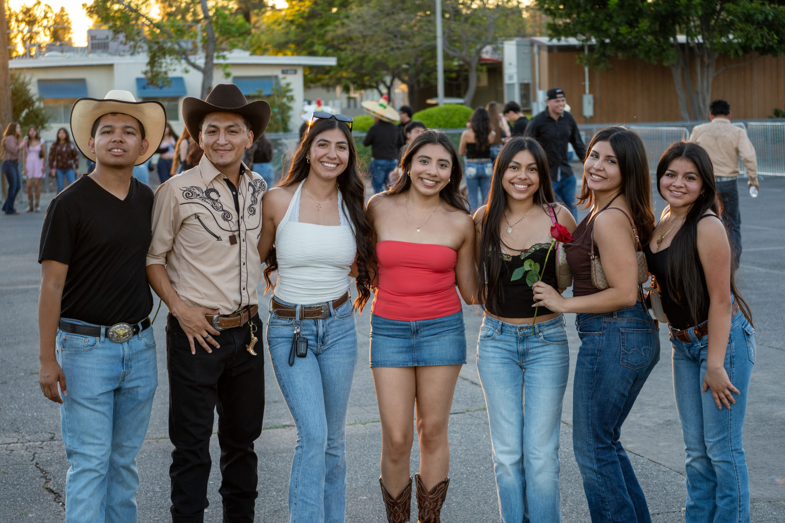 a group of students in cowboy hats and boots pose for a picture holding a rose