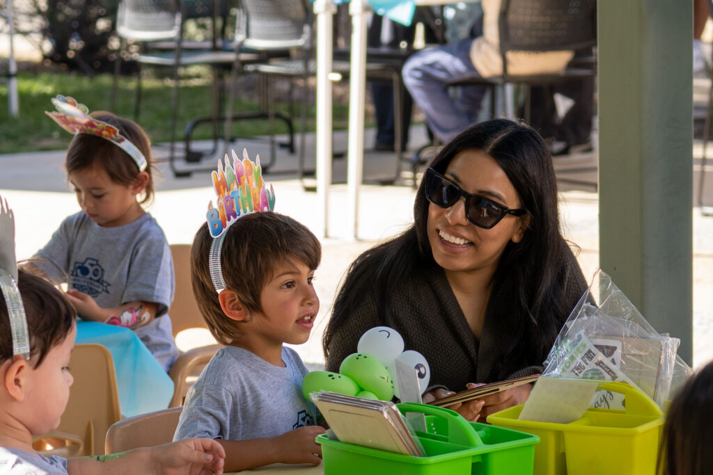 a woman with sunglasses smiles at a child 