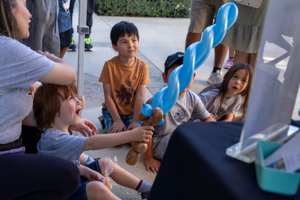 kids sitting down with a balloon sword