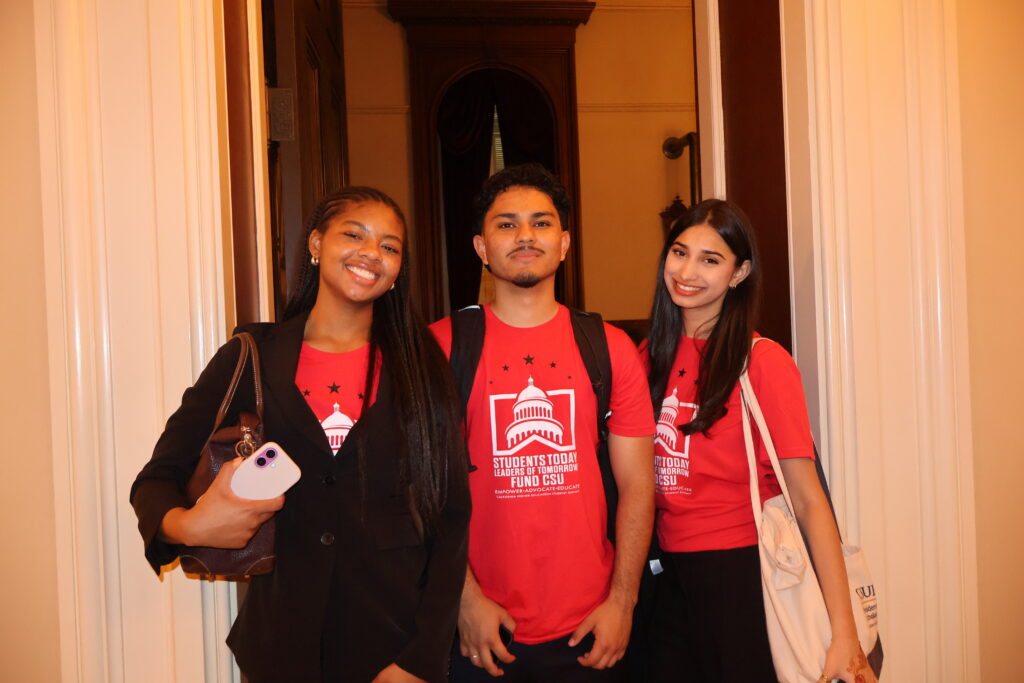 a trio of college students in red shirts pose for a picture 
