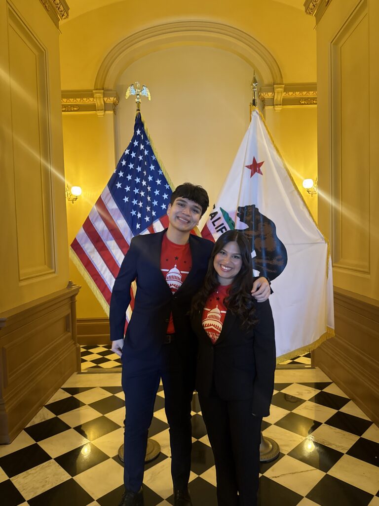 a young man and woman pose for a picture in front of flags