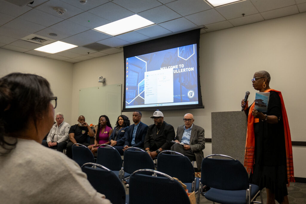 Group of people sit in chairs with a projector and an alumni speaker at the front of the room