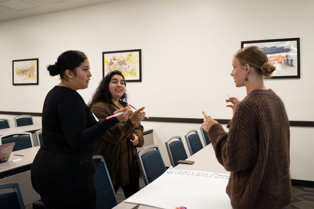a trio of young woman talk to one another 