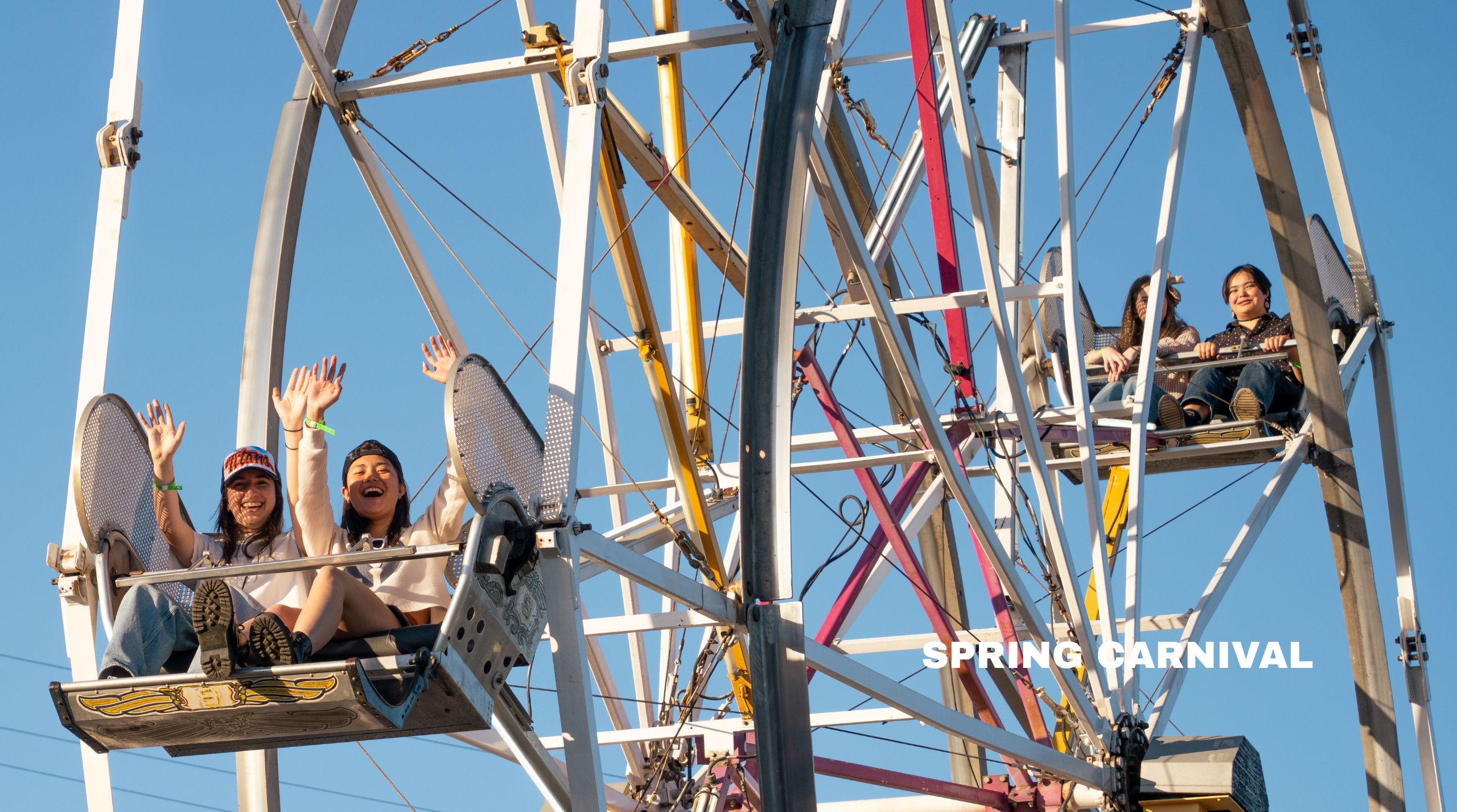two young woman smile on a ferris wheel