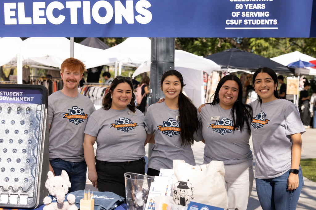 a group of college students in grey shirts pose for a picture under a canopy 