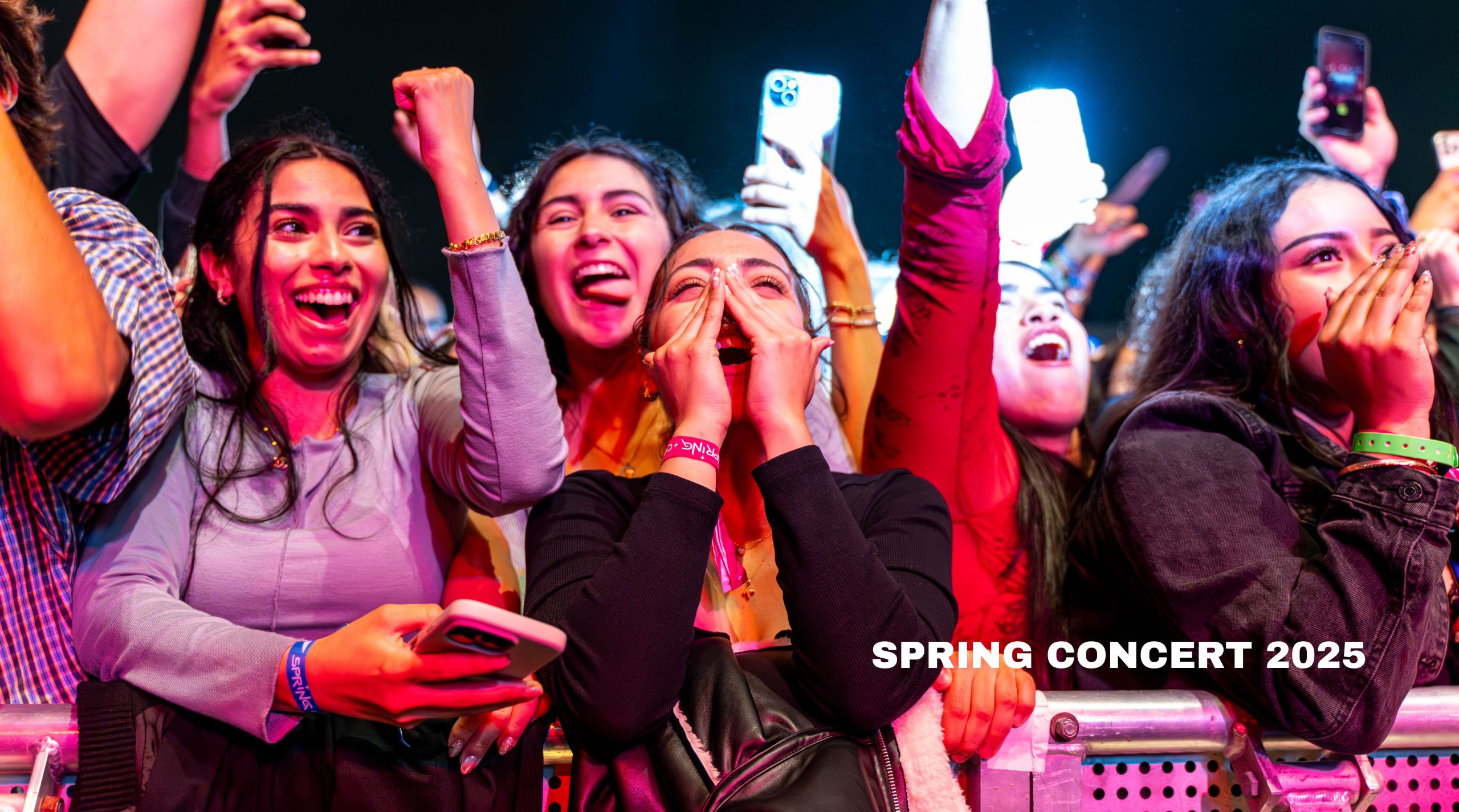 a group of people screaming and smiling in a barricade at a concert