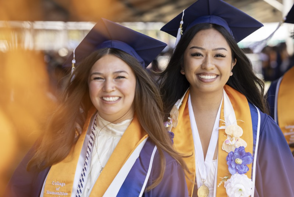 two smiling college graduates in regalia 
