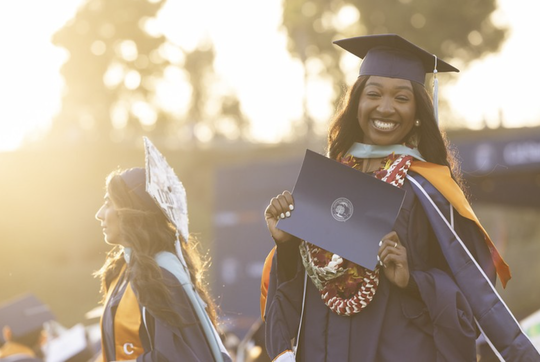 a graduating college student smiles for a photo in regalia