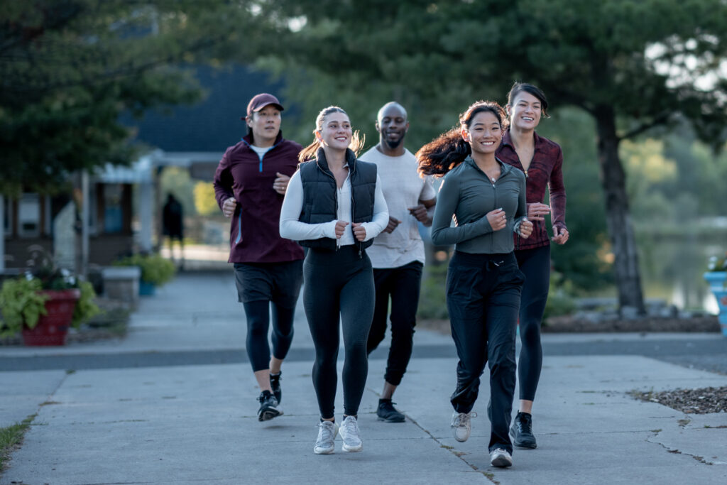 A group of diverse people jogging together on a scenic park trail, showcasing active and healthy lifestyles. 