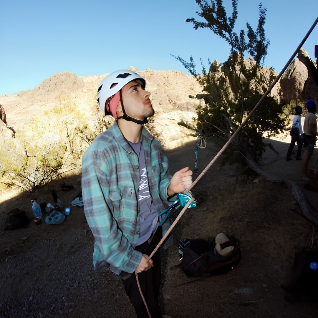 19 a young man holds a climbing rope at the bottom of a mountain