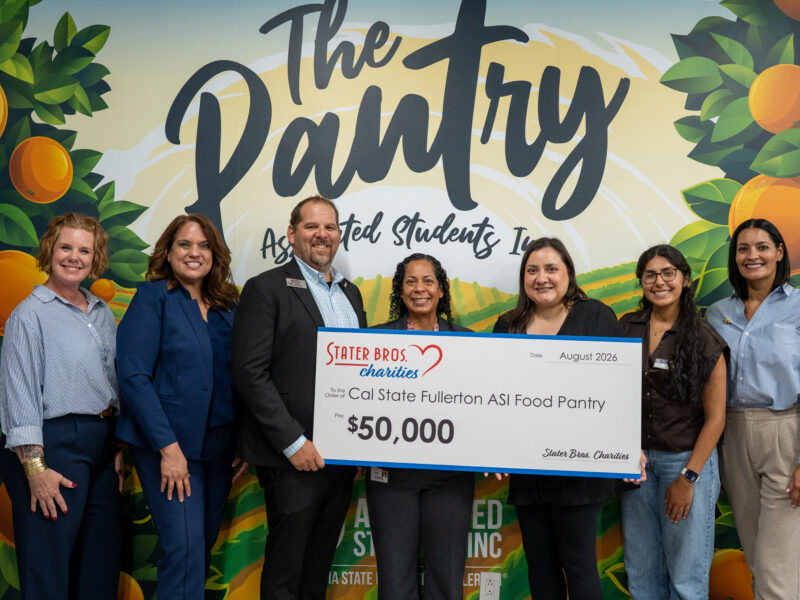 a group of people hold up a giant check donation