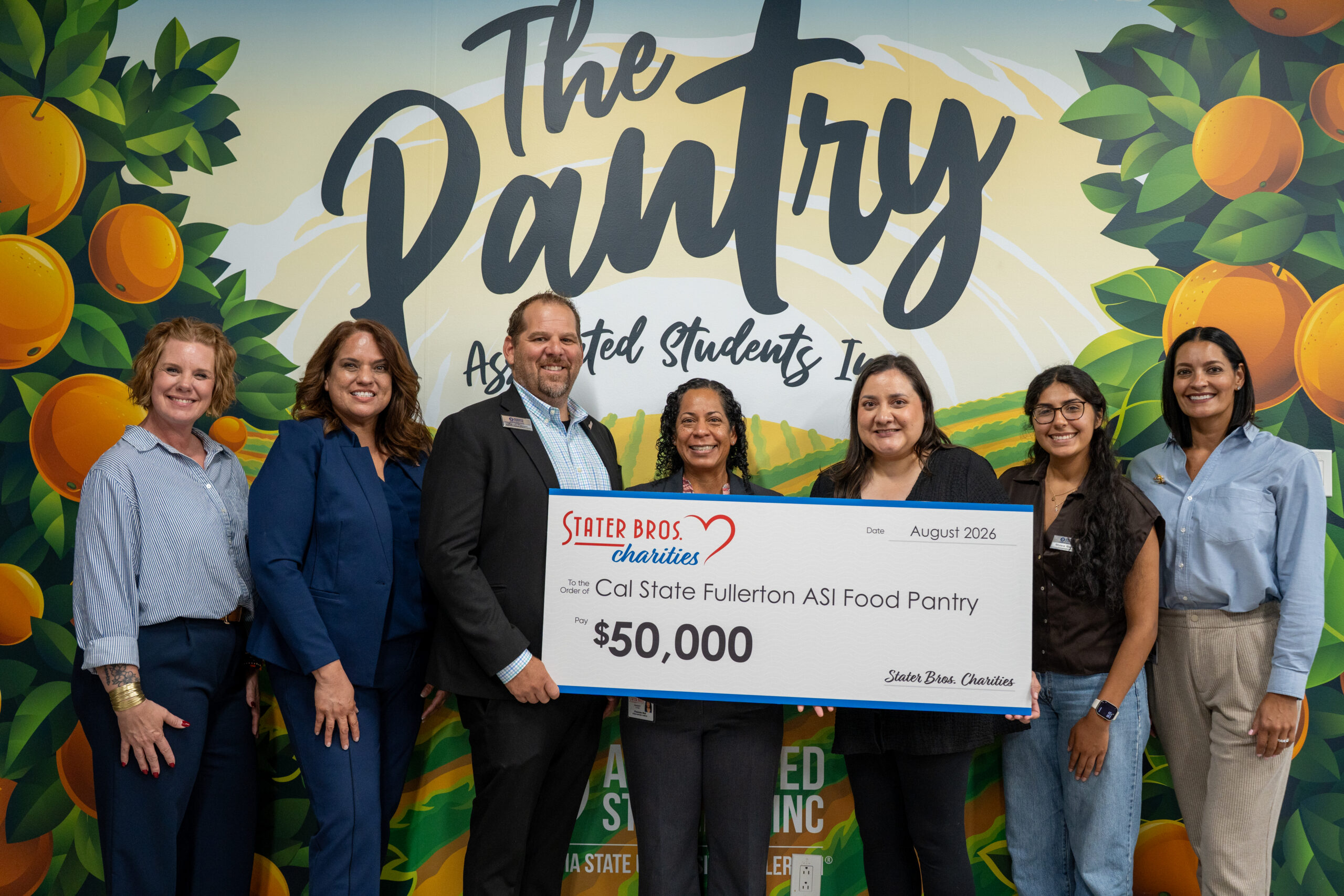 a group of people hold up a giant check donation