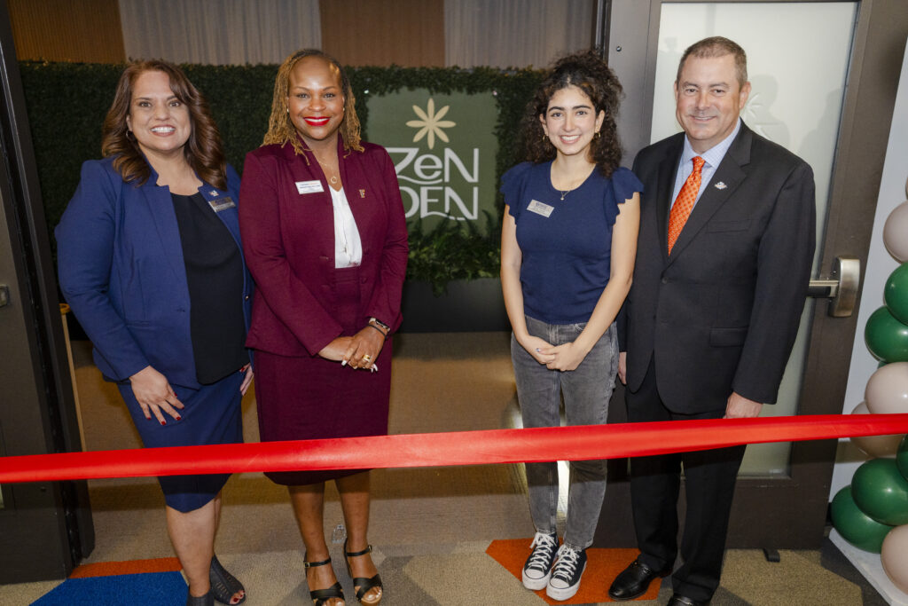 a group of people dressed in professional clothes pose in front of a ribbon cutting