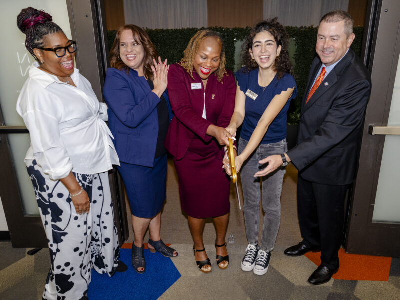 ASI and University leadership use large scissors to cut the ribbon in from the of the zen den