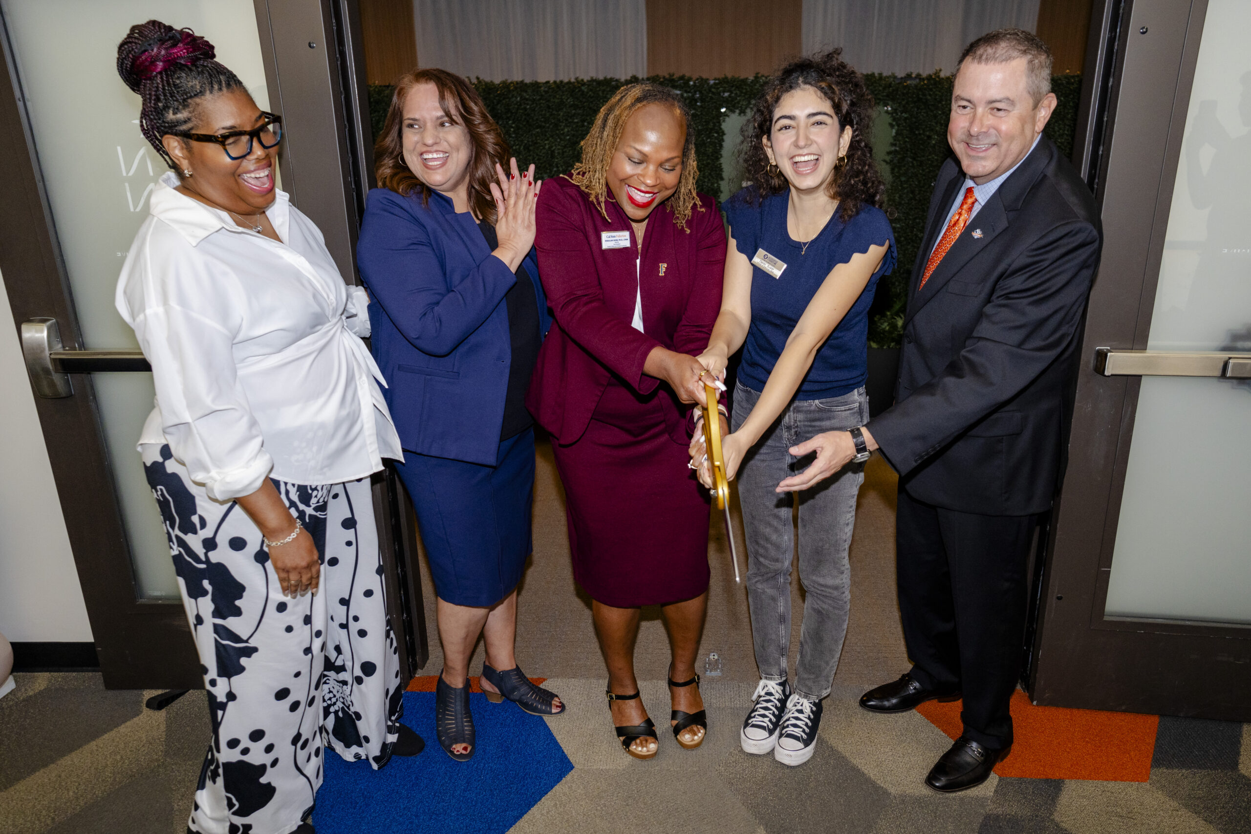 ASI and University leadership use large scissors to cut the ribbon in from the of the zen den