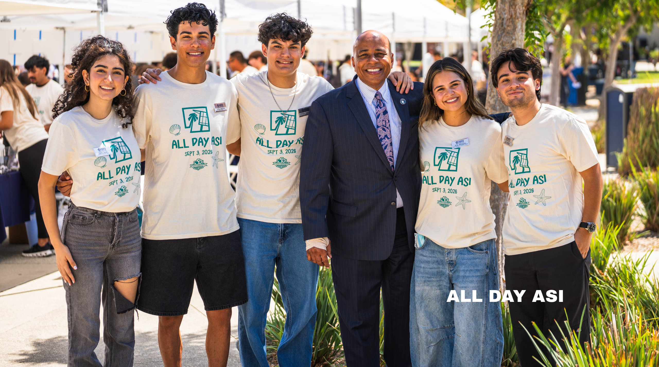 a group of college students pose with a man in a suit
