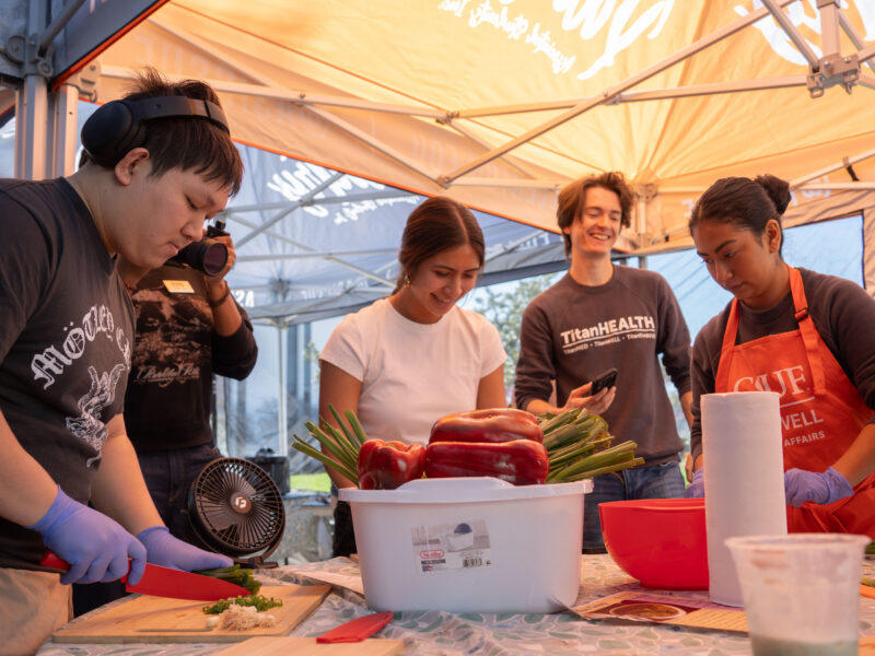 a group of college students laughing and cooking together