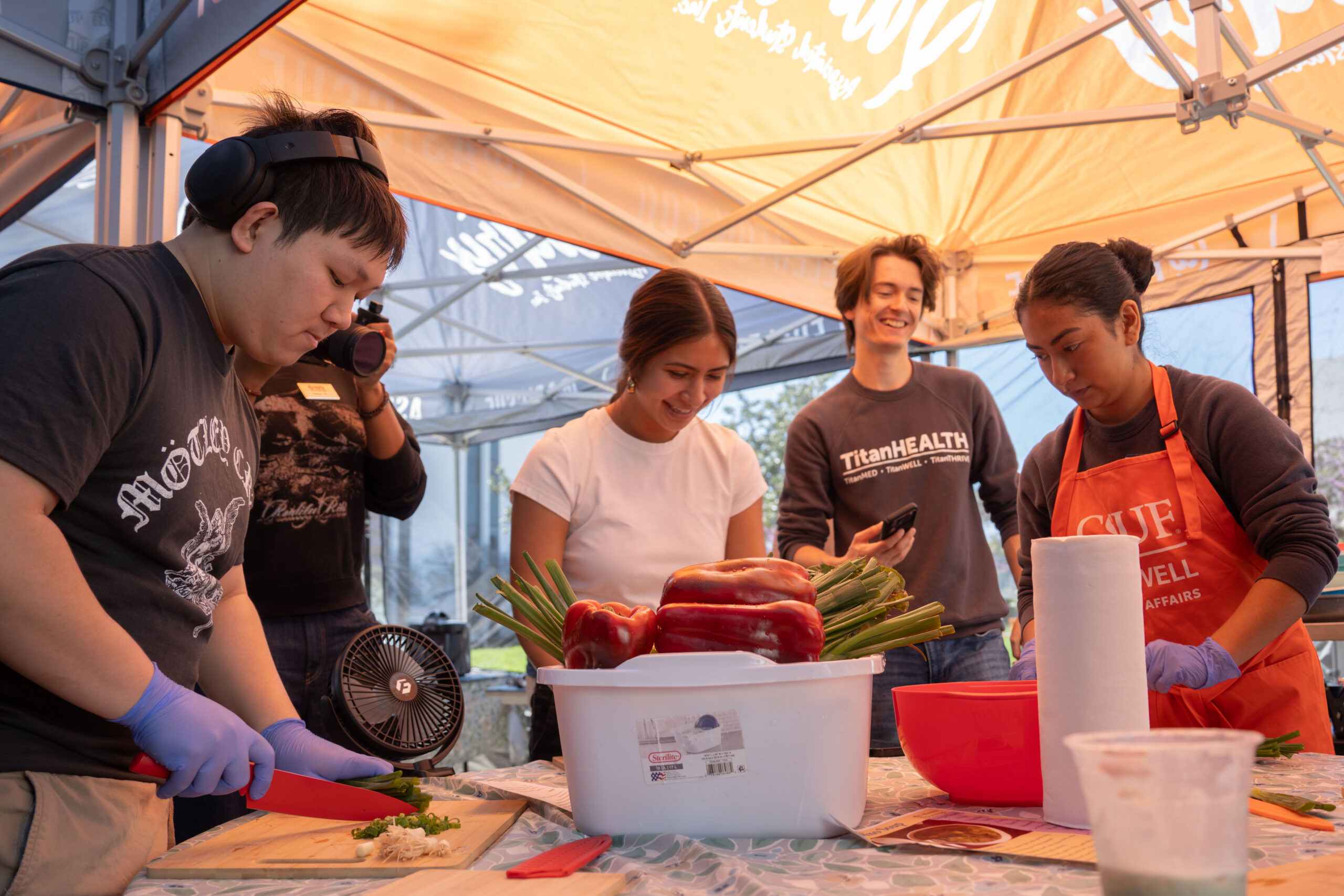 a group of college students laughing and cooking together