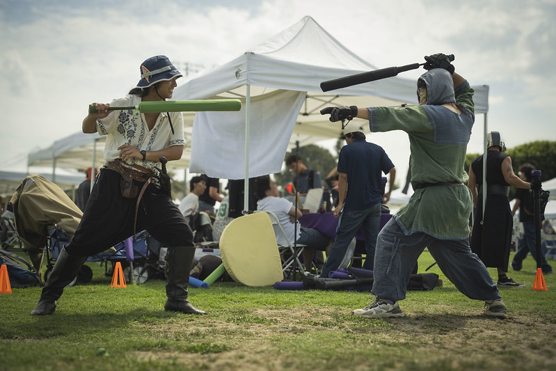 two students from a larping club have a fake sword fight with nerf swords