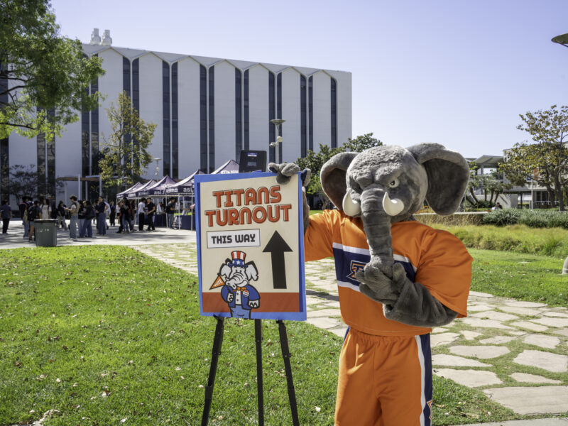 an elephant mascot standing in front of a sign