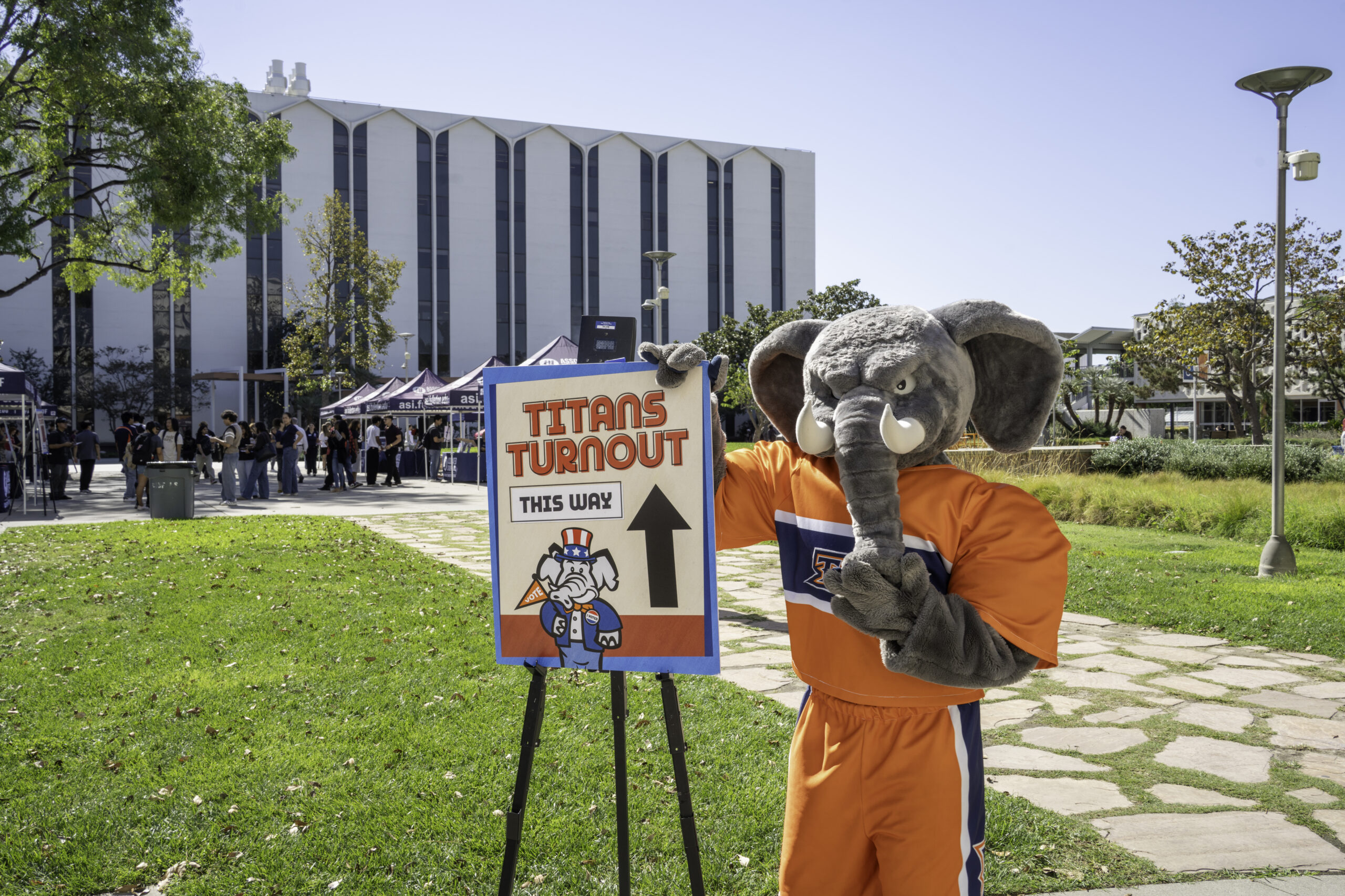 an elephant mascot standing in front of a sign